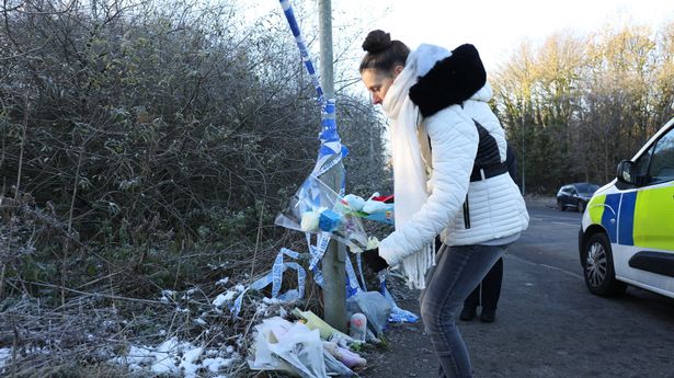 A member of the public leaves a stuffed toy and flowers near the scene where 'Baby A' was found