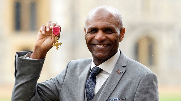 Luther Blissett poses with their medal after being appointed an Officer of the Order of the British Empire (OBE)