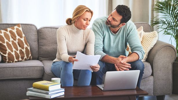 Laptop, couple and documents for finance in home living room on sofa for budget, taxes or savings. Computer, serious and sad man and woman with paperwork for financial crisis, debt and bills in house