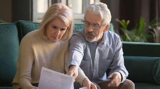 Serious grey haired mature couple calculating bills, checking finances together at home, senior retired old family reading documents, insurance paper, worried about loan, bankruptcy or money problem