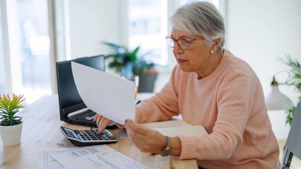 Senior caucasian woman checking pension documents, loan, e-banking, doing paperwork with laptop, mortgage, paying domestic bills at home