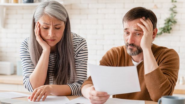 Sad disappointed mature middle-aged couple family wife and husband counting funds, savings, declarations, investments,paperwork, financial documents, bankruptcy, court case, bills, pension at home.