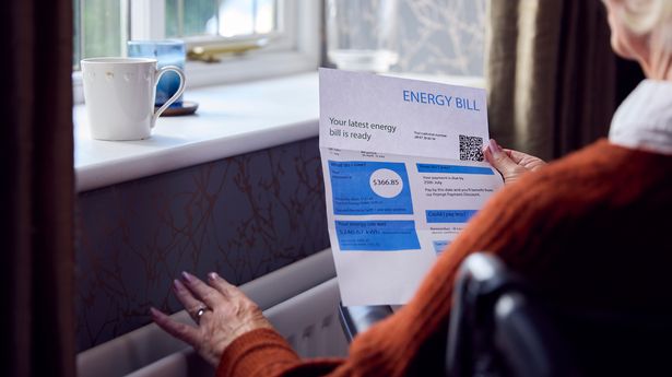 Senior Woman In Wheelchair With USA Energy Bill By Radiator In Cost Of Living Energy Crisis