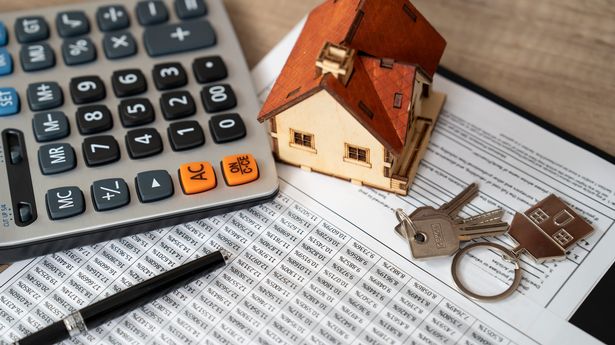 Wooden house sitting on finance documents